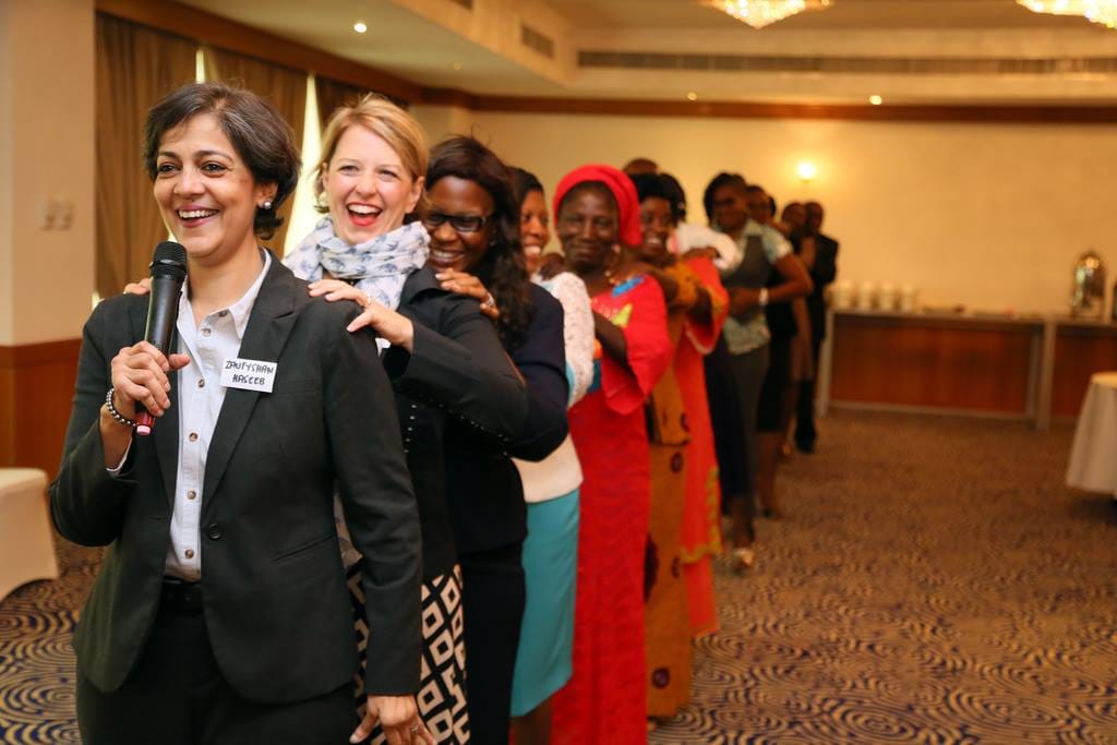 Collaborative design session with hands placing figurines on a detailed miniature landscape model